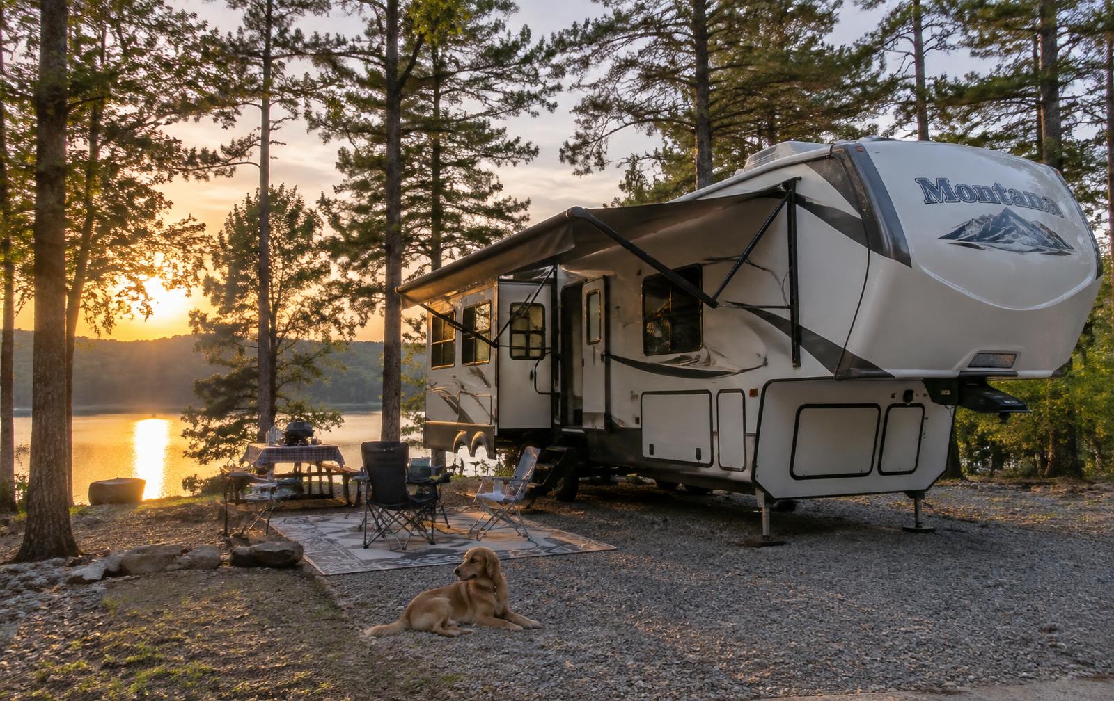 Fifth wheel RV parked at a wooded lakeside campsite in North Georgia at sunset